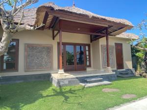 a small house with a porch and a grass yard at Medewi Surf Villa Luxury in Airsatang