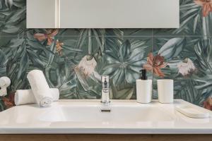 a bathroom sink with two toothbrushes and a flower wallpaper at Casa Oceano Mare BIG in Pozzallo