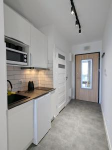 a kitchen with white cabinets and a sink and a window at Irisapart A65 in Warsaw