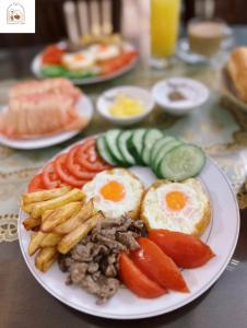 a plate of food with eggs and tomatoes and french fries at Chi's Homestay & Coffee in Hue