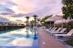 una piscina con tumbonas y sombrillas en un complejo en Sentral Wynwood en Miami