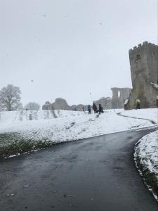 un grupo de personas caminando en la nieve cerca de un castillo en Vale View, en Denbigh