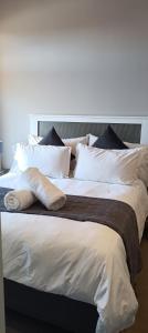 ein großes Bett mit weißer Bettwäsche und Kissen darauf in der Unterkunft Menlyn Maine Trilogy Apartment 808 in Pretoria