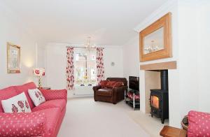 a living room with a red couch and a fireplace at Kissing Gate Cottage in Ebrington