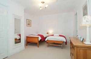 a white bedroom with two beds and a mirror at Kissing Gate Cottage in Ebrington