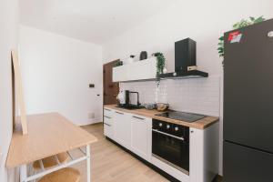 a kitchen with white appliances and a black refrigerator at Ballaro' House - rooms with shared kitchen in Palermo