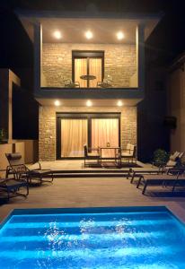 una piscina frente a un edificio con sillas en Epos Villas & Luxury Studios en Paliouri