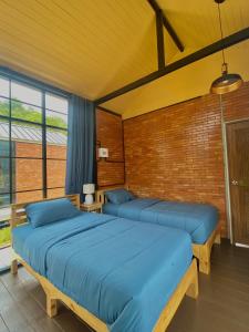 two beds in a room with blue sheets at The Maewin Coffee & Cottage Economy Twin Room in Ban Yang Huai Tong