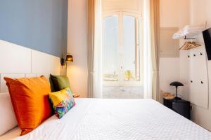 1 dormitorio con cama blanca y almohadas coloridas en Magnini Rooms en Cagliari