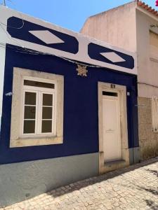 a blue building with two windows and a white door at Cozy family apartment in Cascais in Cascais
