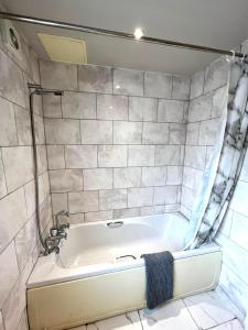 a bath tub in a bathroom with a tile wall at Stunning 1 Bed flat in Canary Wharf FREE parking in London