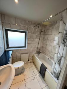 a bathroom with a toilet and a tub and a sink at Stunning 1 Bed flat in Canary Wharf FREE parking in London
