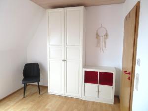 una stanza con un armadietto bianco e una sedia nera di Ferienwohnung Nadine a Calw