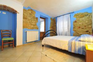 Schlafzimmer mit blauen Wänden, einem Bett und einem Stuhl in der Unterkunft Albus Guest House in Baunei