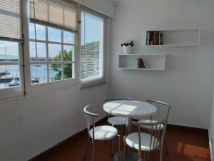 uma mesa e cadeiras num quarto com janelas em SEASTAR nº36 em Horta