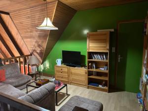 uma sala de estar com um sofá e uma parede verde em Chambres d'hôtes du Theven em Plougoulm