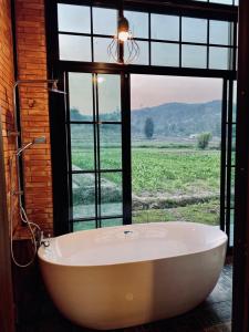 una grande vasca da bagno in una stanza con finestra di The Maewin Coffee & Cottage Economy Twin Room a Ban Yang Huai Tong