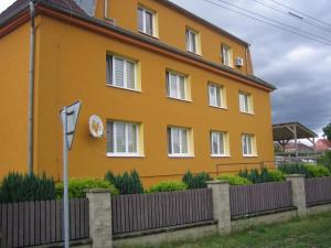 een geel huis met een hek ervoor bij Apartmány Polepy in Polepy