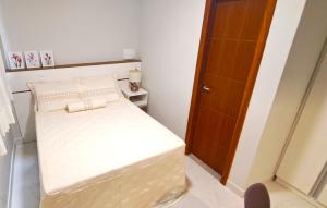 um pequeno quarto com uma cama e uma porta de madeira em Flat da Eliete e Admilson 2 em Porto Seguro