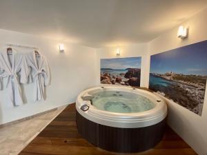 a jacuzzi tub in a bathroom with paintings on the wall at Mieuxqualhotel jacuzzi privatif Le rond in Bordeaux