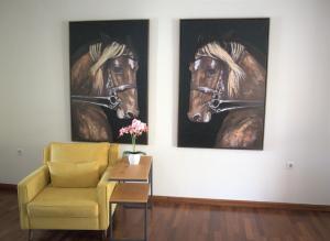 a living room with two paintings of horses on the wall at Kouros At The Park in Alexandroupoli