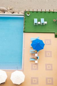 una persona sentada bajo un paraguas azul junto a una piscina en MantaHost Hotel en Manta