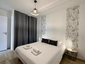 Un dormitorio con una cama blanca con toallas. en LES FORGERONS - Chaleureux, en Mont-de-Marsan