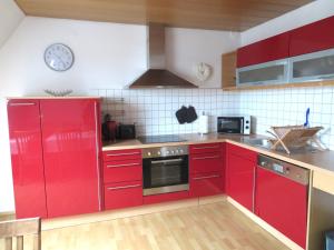 Ferienwohnung Nadine في كلو: مطبخ مع دواليب حمراء وساعة على الحائط