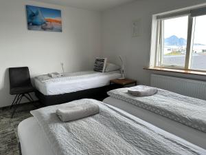 um quarto com 3 camas e uma cadeira e uma janela em Guesthouse Dyngja em Höfn