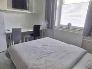 a bedroom with a white bed and a desk and a table at Studio Apartment 14 - 2L2 in Essen