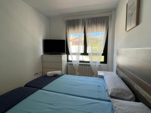 a bedroom with a blue bed and a window at NUEVO LLANO JOB&FAMILY in Puebla de Alfindén