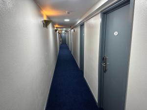 długi korytarz z niebieskim dywanem i drzwiami w obiekcie Hotel EUROPACITY w Brukseli