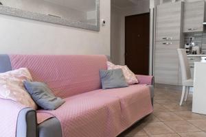 una sala de estar con un sofá rosa con almohadas. en Casetta 46, en Ostia Antica