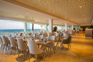 um restaurante com mesas e cadeiras e o oceano em Hotel Torre del Mar - Ibiza em Playa d'en Bossa