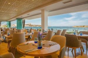 a restaurant with tables and chairs and a view of the ocean at Hotel Torre del Mar - Ibiza in Playa d'en Bossa