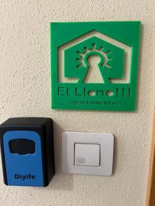 a lightswitch with a green and black sign on a wall at El Llano 3 in Puebla de Alfindén