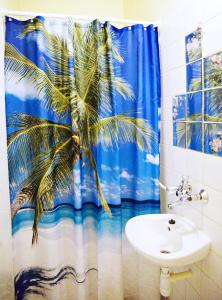 a bathroom with a palm tree shower curtain and a sink at Jocó Panzió in Nyíregyháza