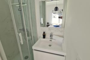 ein Badezimmer mit einem weißen Waschbecken und einer Dusche in der Unterkunft Le Jaures 4 - T2 - 1er Etage in Hennebont