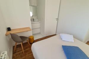 ein Schlafzimmer mit einem Bett, einem Schreibtisch und einem Stuhl in der Unterkunft Le Jaures 4 - T2 - 1er Etage in Hennebont
