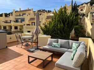 a patio with a couch and a table and some buildings at Entire Bungalow style villa in La Manga Club in Atamaría