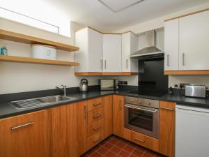 una cocina con armarios blancos y encimeras negras en Plum Hill Studio en Oswestry