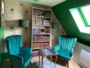 two chairs and a table in a room with green walls at Le gîte du Sorcier 89 in Avallon