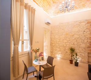 a dining room with a table and chairs and a stone wall at Magnini Rooms in Cagliari