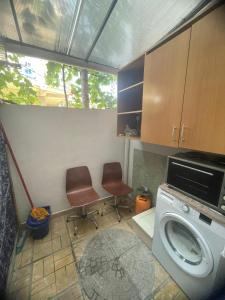 une petite cuisine avec un lave-linge et deux chaises dans l'établissement Flat, à Tirana