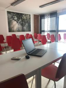 un ordenador portátil sobre una mesa en una habitación con sillas rojas en Albergo Guido Reni, en Turín