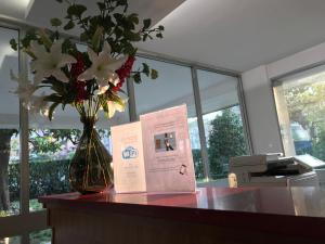 un livre et un vase avec des fleurs sur un bureau dans l'établissement Albergo Guido Reni, à Turin