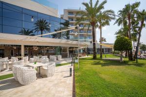 a building with a table and chairs and palm trees at Hotel Torre del Mar - Ibiza in Playa d'en Bossa