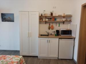 uma pequena cozinha com armários brancos e um micro-ondas em Gästewohnung Fischer em Strehla