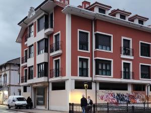 un edificio rojo y blanco con gente parada frente a él en Ribeles Luxury Flat, en Arenas de Cabrales