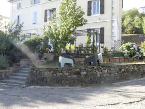 una pared de piedra con sillas y un árbol frente a un edificio en la maison du lac, en Aubin